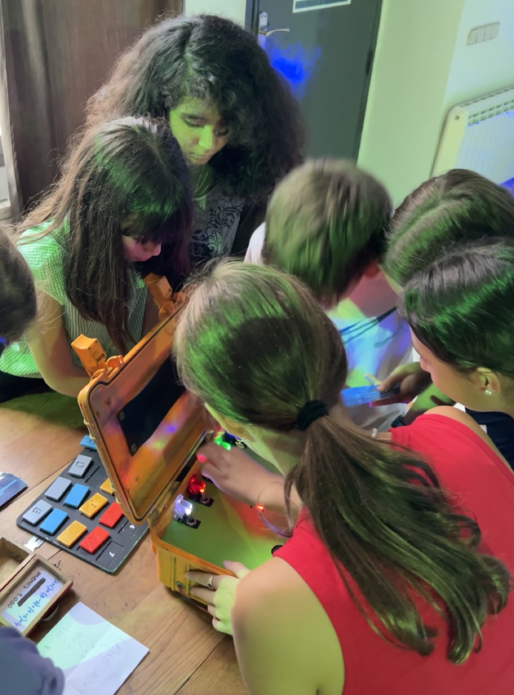 Equipo de niños jugando Stop Max en una sala con iluminación inmersiva, examinando pistas en mesa con concentración