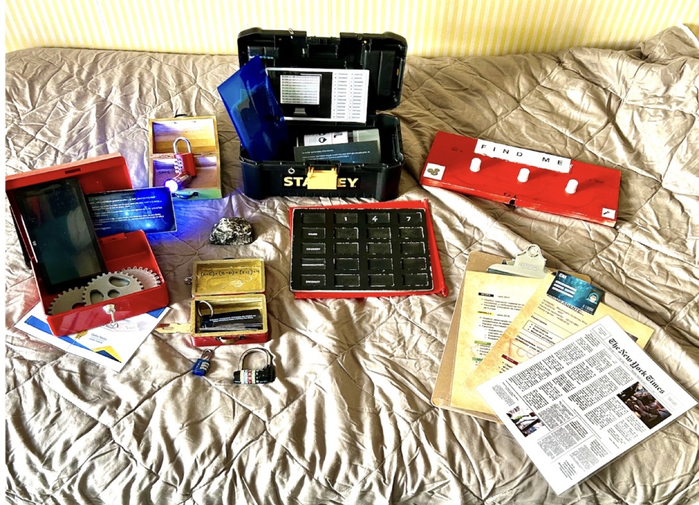 Materiales del escape room Stop Max desplegados: caja de espía con candados, mensajes cifrados, mapas, periódico con pistas y dispositivos del juego